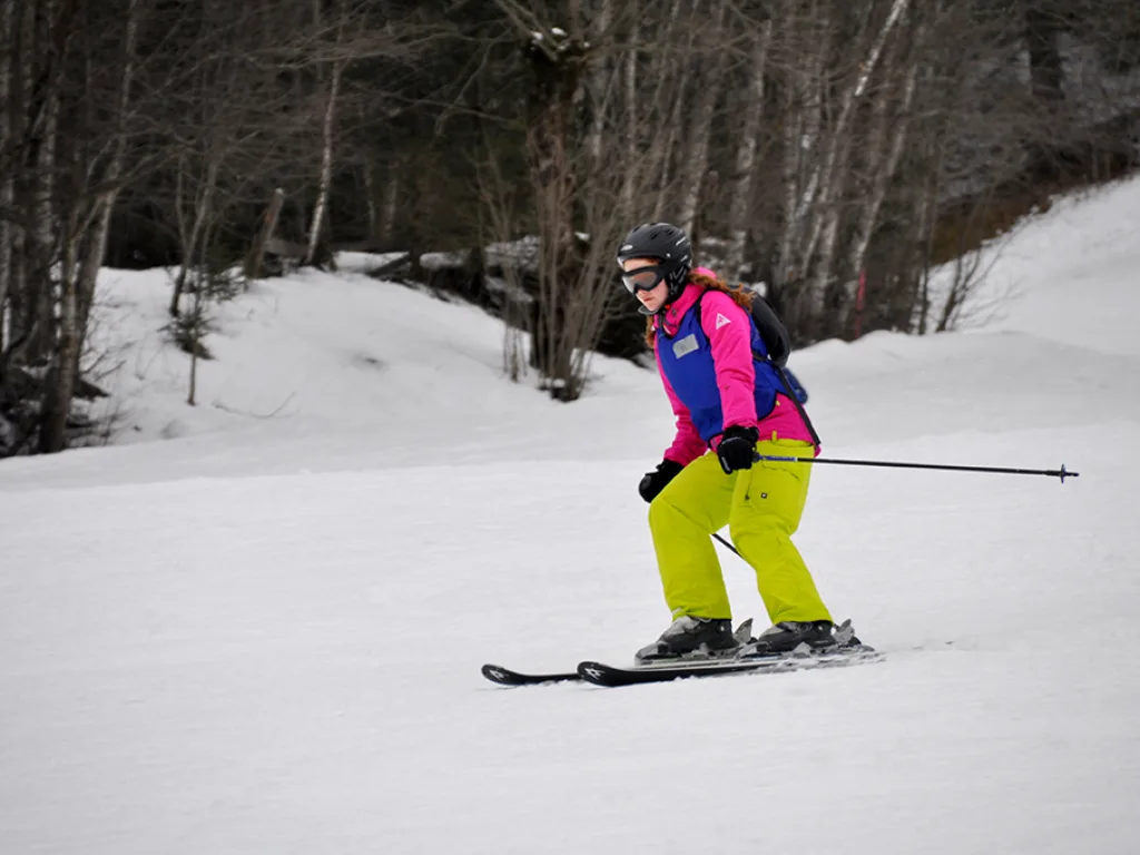 Skifahrerin in gelber Hose auf der Piste.
